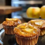 Close-up view of a freshly baked Apfel Zimt Muffin, showcasing a golden-brown crust and apple pieces.
