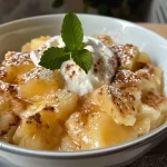 Close-up view of a bowl of Bratapfelkompott with a swirl of cinnamon cream on top.