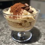 A close-up view of a creamy Keto Tiramisu Mousse topped with cocoa powder and coffee beans.